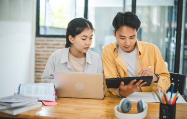 Ödev yapan genç üniversite öğrencileri, işbirliği yapan araştırma planı kavramları ve stratejileri tartışıyor. Dizüstü bilgisayarlarda ve tablet bilgisayarlarda sunumları hazırlayın.
