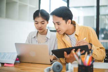 Ödev yapan genç üniversite öğrencileri, işbirliği yapan araştırma planı kavramları ve stratejileri tartışıyor. Dizüstü bilgisayarlarda ve tablet bilgisayarlarda sunumları hazırlayın.