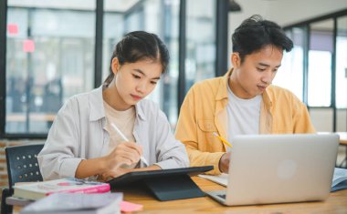 Ödev yapan genç üniversite öğrencileri, işbirliği yapan araştırma planı kavramları ve stratejileri tartışıyor. Dizüstü bilgisayarlarda ve tablet bilgisayarlarda sunumları hazırlayın.