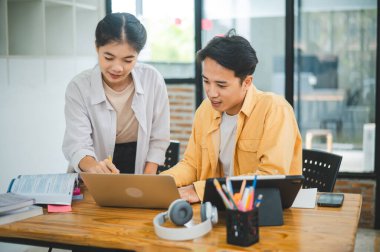 Ödev yapan genç üniversite öğrencileri, işbirliği yapan araştırma planı kavramları ve stratejileri tartışıyor. Dizüstü bilgisayarlarda ve tablet bilgisayarlarda sunumları hazırlayın.