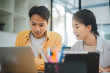 Ödev yapan genç üniversite öğrencileri, işbirliği yapan araştırma planı kavramları ve stratejileri tartışıyor. Dizüstü bilgisayarlarda ve tablet bilgisayarlarda sunumları hazırlayın.