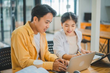 Ödev yapan genç üniversite öğrencileri, işbirliği yapan araştırma planı kavramları ve stratejileri tartışıyor. Dizüstü bilgisayarlarda ve tablet bilgisayarlarda sunumları hazırlayın.