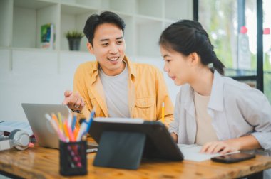 Ödev yapan genç üniversite öğrencileri, işbirliği yapan araştırma planı kavramları ve stratejileri tartışıyor. Dizüstü bilgisayarlarda ve tablet bilgisayarlarda sunumları hazırlayın.