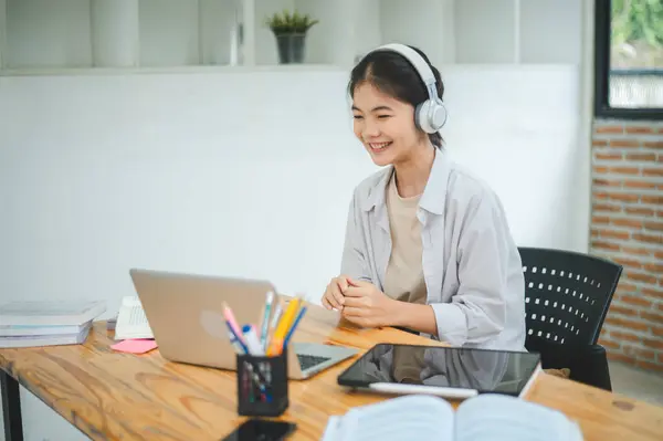 Teenage Asian students  wearing a headphone are communicating through video conferencing for online learning. In a video Teenage Asian students  wearing a headphone are communicating through video conferencing for online learning. In a video conferen
