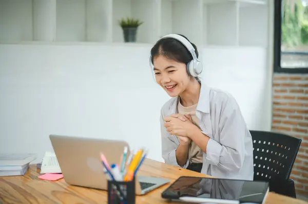 Teenage Asian students  wearing a headphone are communicating through video conferencing for online learning. In a video Teenage Asian students  wearing a headphone are communicating through video conferencing for online learning. In a video conferen