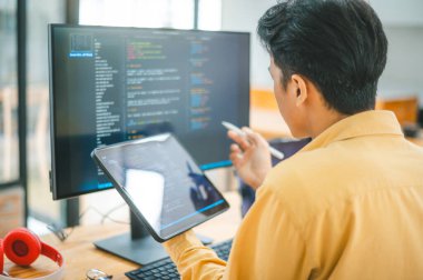 Yazılım şirketinin ofisinde kodlama, yazılım geliştirme ve web tasarımı üzerine çalışan genç bir programcı. Teknoloji geliştirme kavramı
