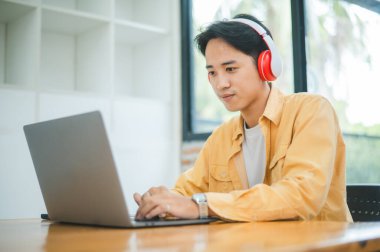 Öğrenci, bir kafede kulaklık takarken dizüstü bilgisayar kullanıyor, internette öğreniyor ve arama yapıyor..