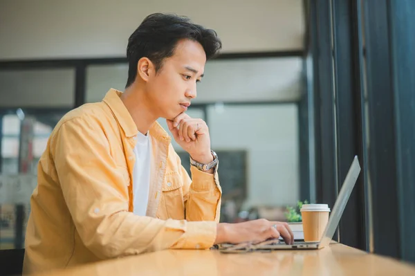 stock image Young Asian college student working and learning on laptop In the cafe. Searching for knowledge online.