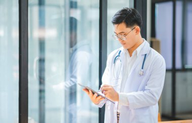 Steteskoplu ve dijital tablet kullanan portre doktoru hastane veya klinikteki sağlık hizmetleri ziyaretçilerine güvenle hazırdır..