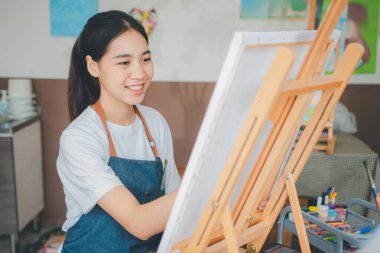 Resim öğrencisi tuvale suluboya resim çiziyor. Stüdyo atölyesinde bazı sanat projeleri yapıyor.