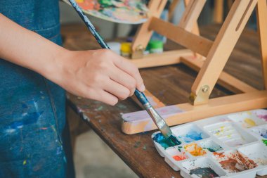 Tablo üzerindeki suluboya resme başlamadan önce resim yapmak için boya fırçası ve suluboya boya boya kullanmanın yakın çekimi.