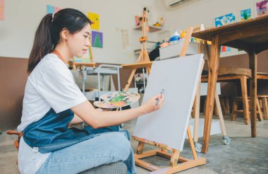 Resim öğrencisi tuvale suluboya resim çiziyor. Stüdyo atölyesinde bazı sanat projeleri yapıyor.