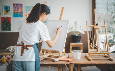 Resim öğrencisi tuvale suluboya resim çiziyor. Stüdyo atölyesinde bazı sanat projeleri yapıyor.