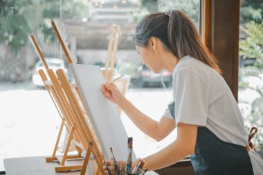 Resim öğrencisi tuvale suluboya resim çiziyor. Stüdyo atölyesinde bazı sanat projeleri yapıyor.