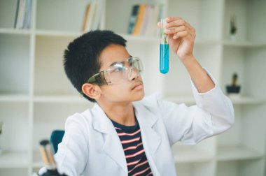 Asyalı erkek bilim öğrencileri mikroskopla bakıyorlar ve sınıfta bitki testleri yapıyorlar. Bitki türleri üzerinde bilimsel deneyler öğrenmek.