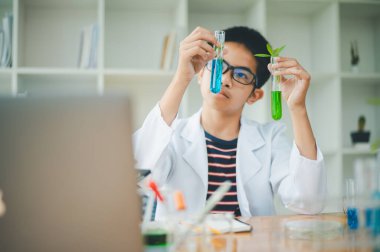 Asyalı erkek bilim öğrencileri mikroskopla bakıyorlar ve sınıfta bitki testleri yapıyorlar. Bitki türleri üzerinde bilimsel deneyler öğrenmek.