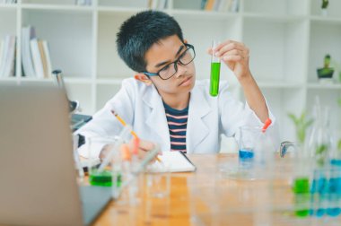 Asyalı erkek bilim öğrencileri mikroskopla bakıyorlar ve sınıfta bitki testleri yapıyorlar. Bitki türleri üzerinde bilimsel deneyler öğrenmek.