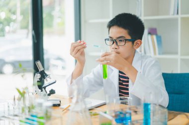 Asyalı erkek bilim öğrencileri mikroskopla bakıyorlar ve sınıfta bitki testleri yapıyorlar. Bitki türleri üzerinde bilimsel deneyler öğrenmek.