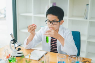 Asyalı erkek bilim öğrencileri mikroskopla bakıyorlar ve sınıfta bitki testleri yapıyorlar. Bitki türleri üzerinde bilimsel deneyler öğrenmek.