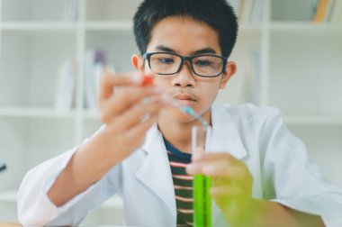 Asyalı erkek bilim öğrencileri mikroskopla bakıyorlar ve sınıfta bitki testleri yapıyorlar. Bitki türleri üzerinde bilimsel deneyler öğrenmek.