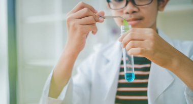 Asyalı erkek bilim öğrencileri mikroskopla bakıyorlar ve sınıfta bitki testleri yapıyorlar. Bitki türleri üzerinde bilimsel deneyler öğrenmek.