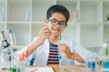 Asyalı erkek bilim öğrencileri mikroskopla bakıyorlar ve sınıfta bitki testleri yapıyorlar. Bitki türleri üzerinde bilimsel deneyler öğrenmek.