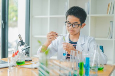 Asyalı erkek bilim öğrencileri mikroskopla bakıyorlar ve sınıfta bitki testleri yapıyorlar. Bitki türleri üzerinde bilimsel deneyler öğrenmek.