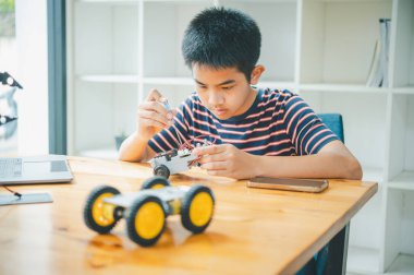 Asyalı çocuk teknoloji robotlarının çalışmalarını öğreniyor ve inceliyor. Teknoloji projesi için ev okulu ve bilim. Çocukluk çocukları hobisi eğlence yaşam tarzı oyuncakları robot teknolojisi.