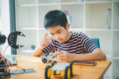 Asyalı çocuk teknoloji robotlarının çalışmalarını öğreniyor ve inceliyor. Teknoloji projesi için ev okulu ve bilim. Çocukluk çocukları hobisi eğlence yaşam tarzı oyuncakları robot teknolojisi.