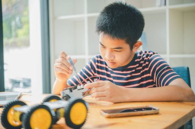 Asyalı çocuk teknoloji robotlarının çalışmalarını öğreniyor ve inceliyor. Teknoloji projesi için ev okulu ve bilim. Çocukluk çocukları hobisi eğlence yaşam tarzı oyuncakları robot teknolojisi.
