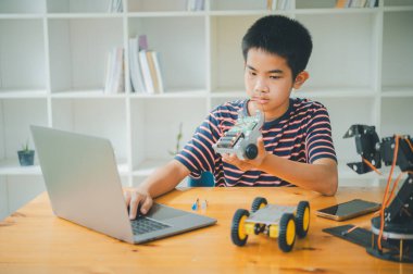 Asyalı çocuk teknoloji robotlarının çalışmalarını öğreniyor ve inceliyor. Teknoloji projesi için ev okulu ve bilim. Çocukluk çocukları hobisi eğlence yaşam tarzı oyuncakları robot teknolojisi.
