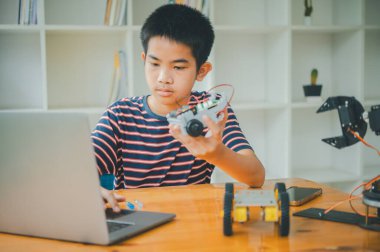 Asyalı çocuk teknoloji robotlarının çalışmalarını öğreniyor ve inceliyor. Teknoloji projesi için ev okulu ve bilim. Çocukluk çocukları hobisi eğlence yaşam tarzı oyuncakları robot teknolojisi.