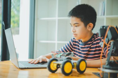 Asyalı çocuk teknoloji robotlarının çalışmalarını öğreniyor ve inceliyor. Teknoloji projesi için ev okulu ve bilim. Çocukluk çocukları hobisi eğlence yaşam tarzı oyuncakları robot teknolojisi.