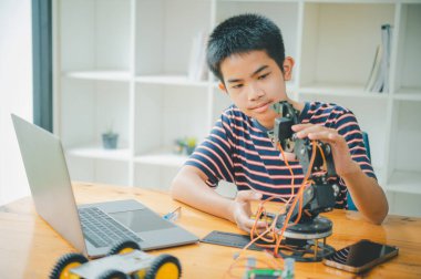 Asyalı çocuk teknoloji robotlarının çalışmalarını öğreniyor ve inceliyor. Teknoloji projesi için ev okulu ve bilim. Çocukluk çocukları hobisi eğlence yaşam tarzı oyuncakları robot teknolojisi.