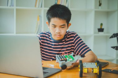 Asyalı çocuk teknoloji robotlarının çalışmalarını öğreniyor ve inceliyor. Teknoloji projesi için ev okulu ve bilim. Çocukluk çocukları hobisi eğlence yaşam tarzı oyuncakları robot teknolojisi.