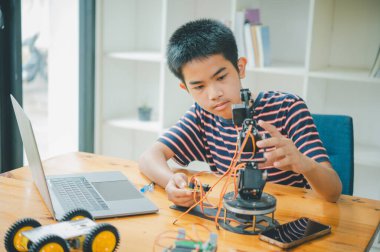 Asyalı çocuk teknoloji robotlarının çalışmalarını öğreniyor ve inceliyor. Teknoloji projesi için ev okulu ve bilim. Çocukluk çocukları hobisi eğlence yaşam tarzı oyuncakları robot teknolojisi.