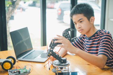 Asyalı çocuk teknoloji robotlarının çalışmalarını öğreniyor ve inceliyor. Teknoloji projesi için ev okulu ve bilim. Çocukluk çocukları hobisi eğlence yaşam tarzı oyuncakları robot teknolojisi.