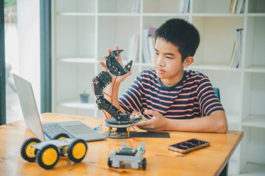 Asyalı çocuk teknoloji robotlarının çalışmalarını öğreniyor ve inceliyor. Teknoloji projesi için ev okulu ve bilim. Çocukluk çocukları hobisi eğlence yaşam tarzı oyuncakları robot teknolojisi.