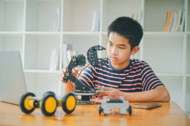 Asyalı çocuk teknoloji robotlarının çalışmalarını öğreniyor ve inceliyor. Teknoloji projesi için ev okulu ve bilim. Çocukluk çocukları hobisi eğlence yaşam tarzı oyuncakları robot teknolojisi.