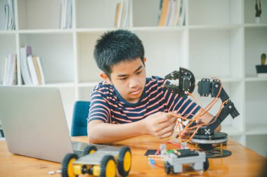 Asyalı çocuk teknoloji robotlarının çalışmalarını öğreniyor ve inceliyor. Teknoloji projesi için ev okulu ve bilim. Çocukluk çocukları hobisi eğlence yaşam tarzı oyuncakları robot teknolojisi.