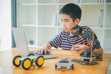 Asyalı çocuk teknoloji robotlarının çalışmalarını öğreniyor ve inceliyor. Teknoloji projesi için ev okulu ve bilim. Çocukluk çocukları hobisi eğlence yaşam tarzı oyuncakları robot teknolojisi.