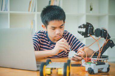 Asyalı çocuk teknoloji robotlarının çalışmalarını öğreniyor ve inceliyor. Teknoloji projesi için ev okulu ve bilim. Çocukluk çocukları hobisi eğlence yaşam tarzı oyuncakları robot teknolojisi.