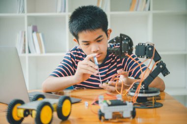 Asyalı çocuk teknoloji robotlarının çalışmalarını öğreniyor ve inceliyor. Teknoloji projesi için ev okulu ve bilim. Çocukluk çocukları hobisi eğlence yaşam tarzı oyuncakları robot teknolojisi.