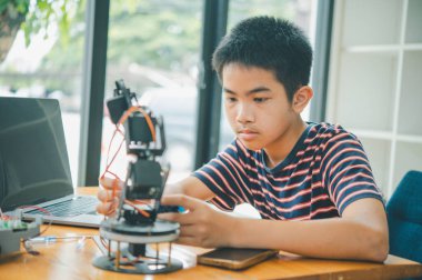 Asyalı çocuk teknoloji robotlarının çalışmalarını öğreniyor ve inceliyor. Teknoloji projesi için ev okulu ve bilim. Çocukluk çocukları hobisi eğlence yaşam tarzı oyuncakları robot teknolojisi.