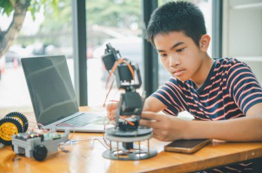 Asyalı çocuk teknoloji robotlarının çalışmalarını öğreniyor ve inceliyor. Teknoloji projesi için ev okulu ve bilim. Çocukluk çocukları hobisi eğlence yaşam tarzı oyuncakları robot teknolojisi.