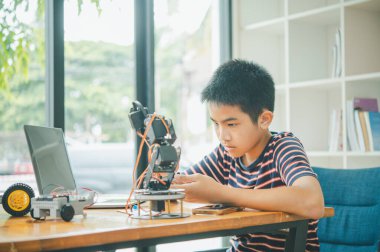 Asyalı çocuk teknoloji robotlarının çalışmalarını öğreniyor ve inceliyor. Teknoloji projesi için ev okulu ve bilim. Çocukluk çocukları hobisi eğlence yaşam tarzı oyuncakları robot teknolojisi.