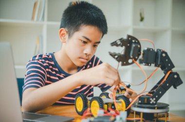 Asyalı çocuk teknoloji robotlarının çalışmalarını öğreniyor ve inceliyor. Teknoloji projesi için ev okulu ve bilim. Çocukluk çocukları hobisi eğlence yaşam tarzı oyuncakları robot teknolojisi.