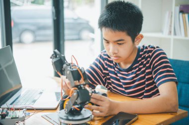 Asyalı çocuk teknoloji robotlarının çalışmalarını öğreniyor ve inceliyor. Teknoloji projesi için ev okulu ve bilim. Çocukluk çocukları hobisi eğlence yaşam tarzı oyuncakları robot teknolojisi.