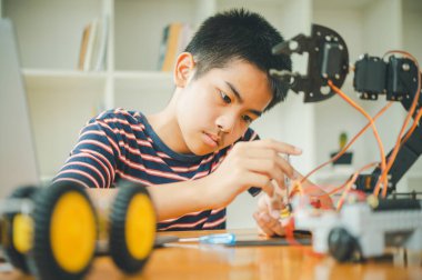 Asyalı çocuk teknoloji robotlarının çalışmalarını öğreniyor ve inceliyor. Teknoloji projesi için ev okulu ve bilim. Çocukluk çocukları hobisi eğlence yaşam tarzı oyuncakları robot teknolojisi.
