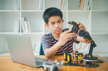 Asyalı çocuk teknoloji robotlarının çalışmalarını öğreniyor ve inceliyor. Teknoloji projesi için ev okulu ve bilim. Çocukluk çocukları hobisi eğlence yaşam tarzı oyuncakları robot teknolojisi.
